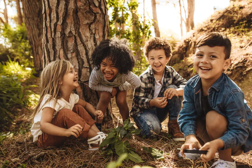 Children sitting near a tree laughing