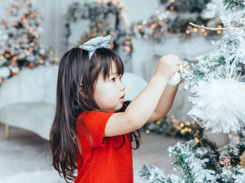 A young girl putting ornaments on a tree